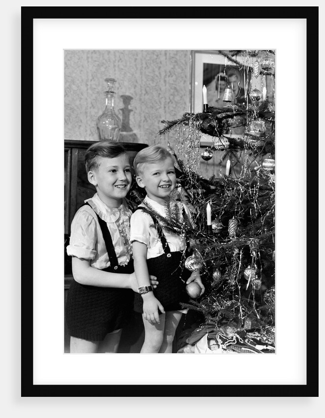 Two brothers look at a Christmas tree in their living room in Germany, ca. 1949 by Anonymous