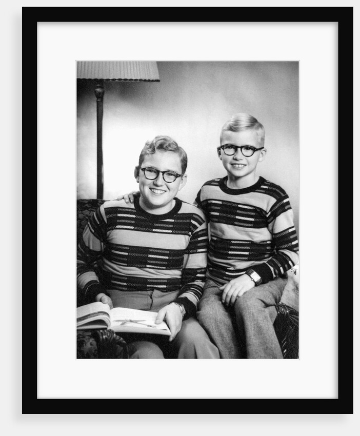 Two brothers pose with a book on their living room couch, ca. 1953 by Anonymous