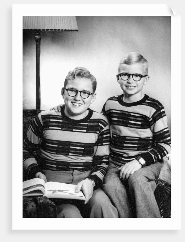 Two brothers pose with a book on their living room couch, ca. 1953 by Anonymous