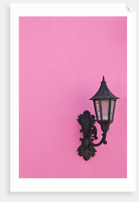 Street lamp on pink wall of Colonial style building by Anonymous