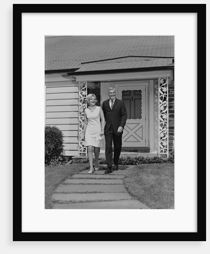 Mature couple walking on sidewalk front of house by Anonymous