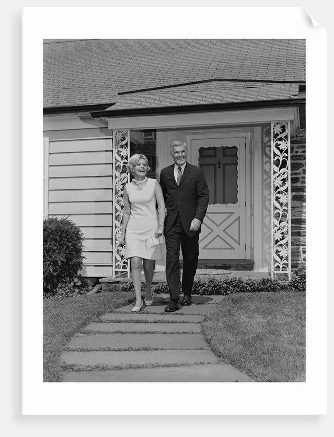Mature couple walking on sidewalk front of house by Anonymous
