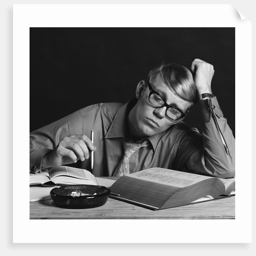 Young man studying reading books leaning on arm by Anonymous