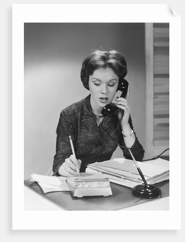 Brunette business woman sitting desk talking telephone writing note on calendar by Anonymous