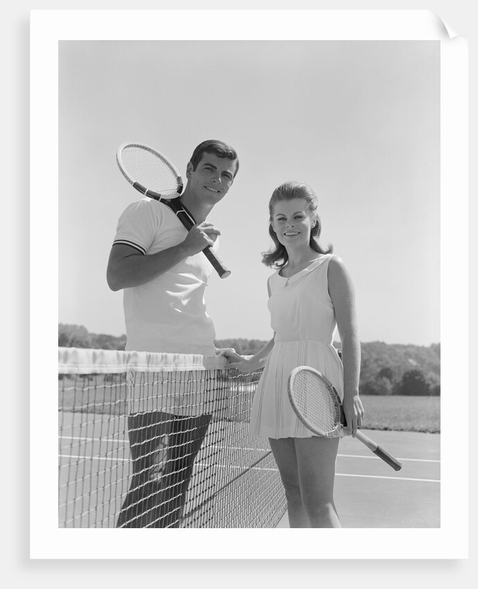 Portrait tennis couple man woman holding racquets standing by net by Anonymous