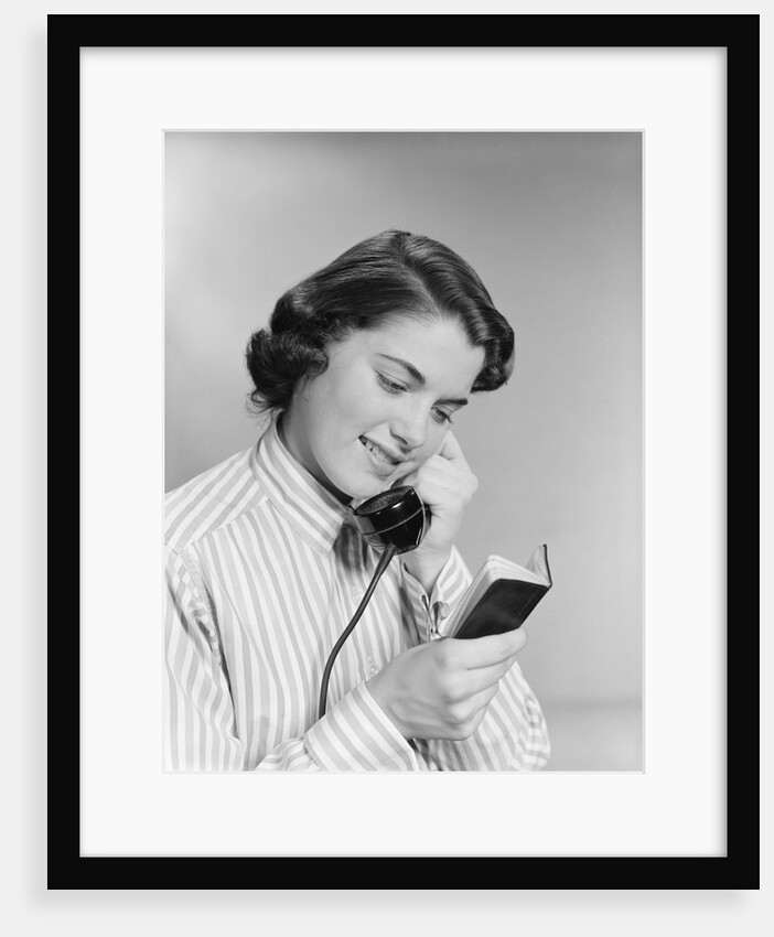 Young woman talking on telephone reading address from little black book by Anonymous