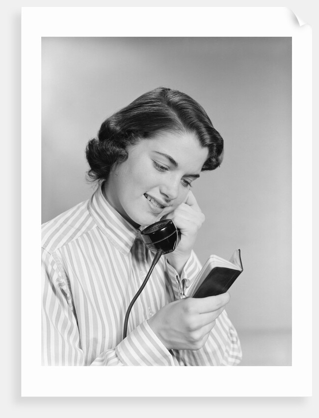 Young woman talking on telephone reading address from little black book by Anonymous