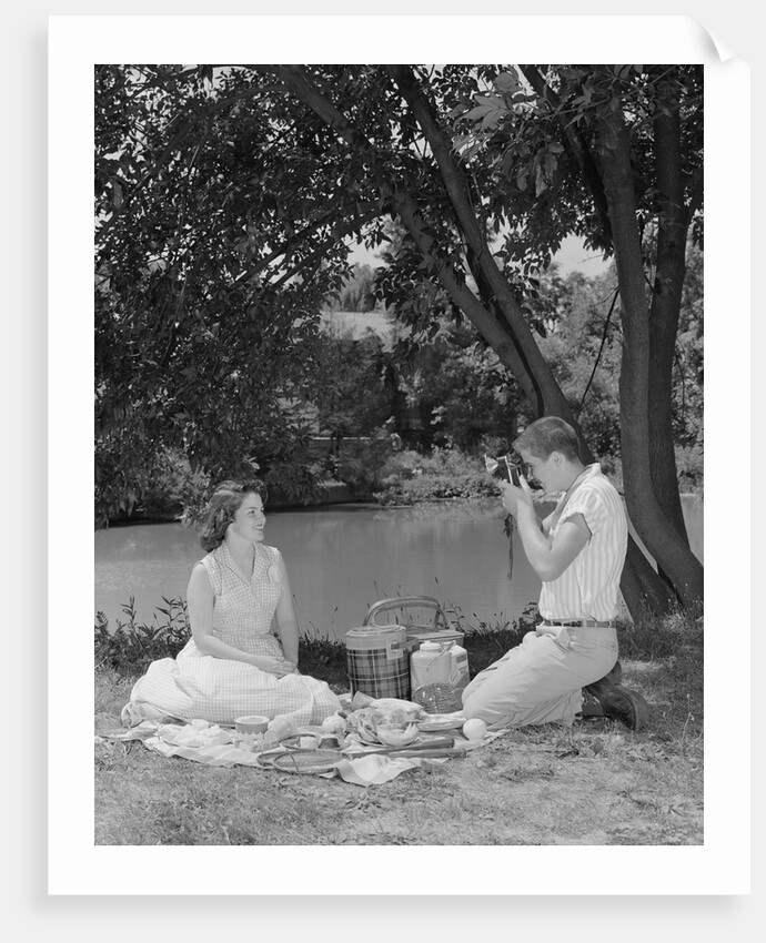 Teenage couple picnic boy taking photograph of girl outdoors by Anonymous