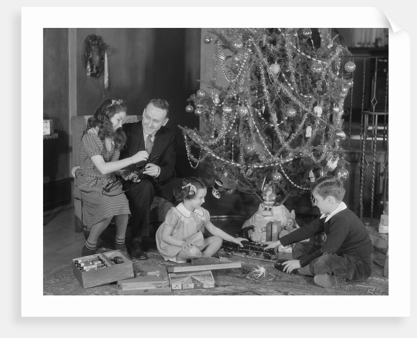 Family christmas photo father two daughters and son with presents and tree by Anonymous