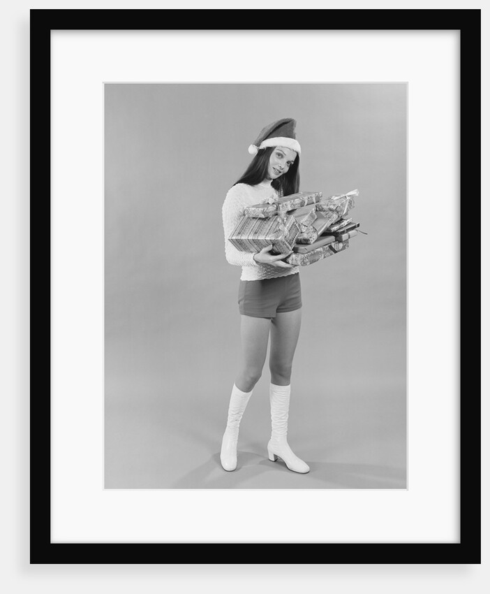 Young woman wearing santa claus hat hot pants go-go boots holding wrapped christmas presents by Anonymous