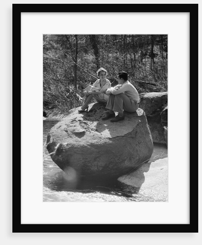 Couple man woman sitting on large rock in stream hugging knees smiling happy romance by Anonymous