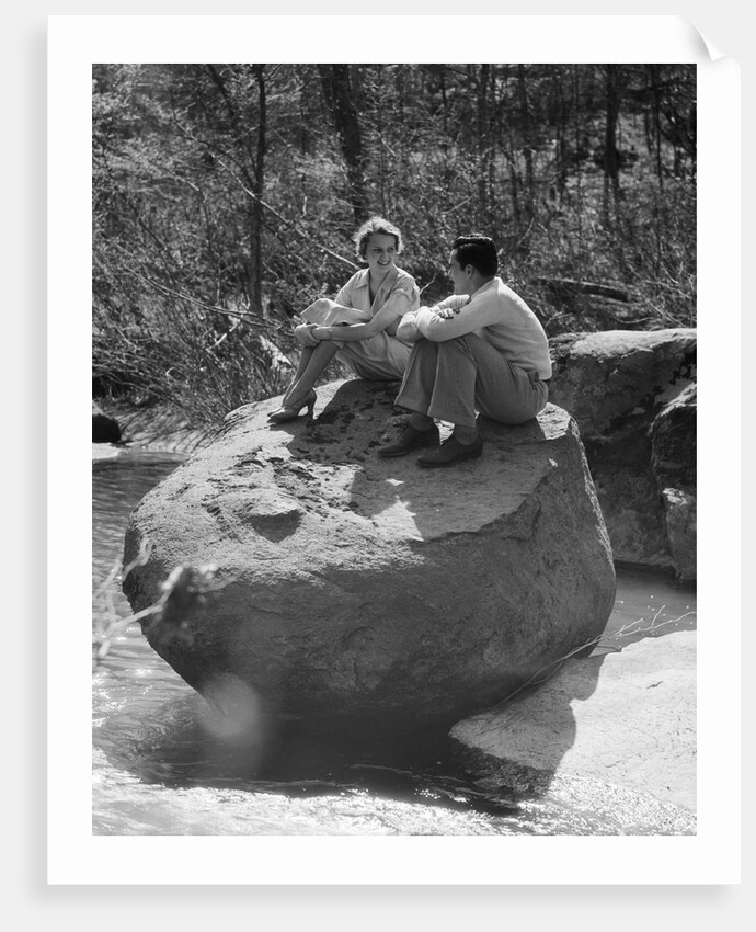 Couple man woman sitting on large rock in stream hugging knees smiling happy romance by Anonymous