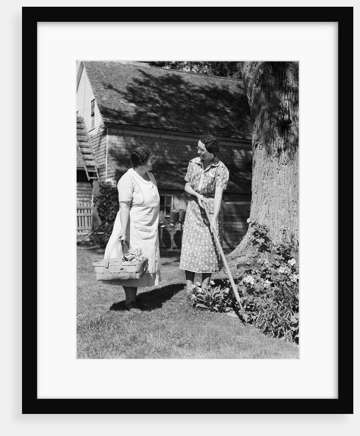 Two women talking in yard one holding garden hoe the other holds basket with flowers by Anonymous