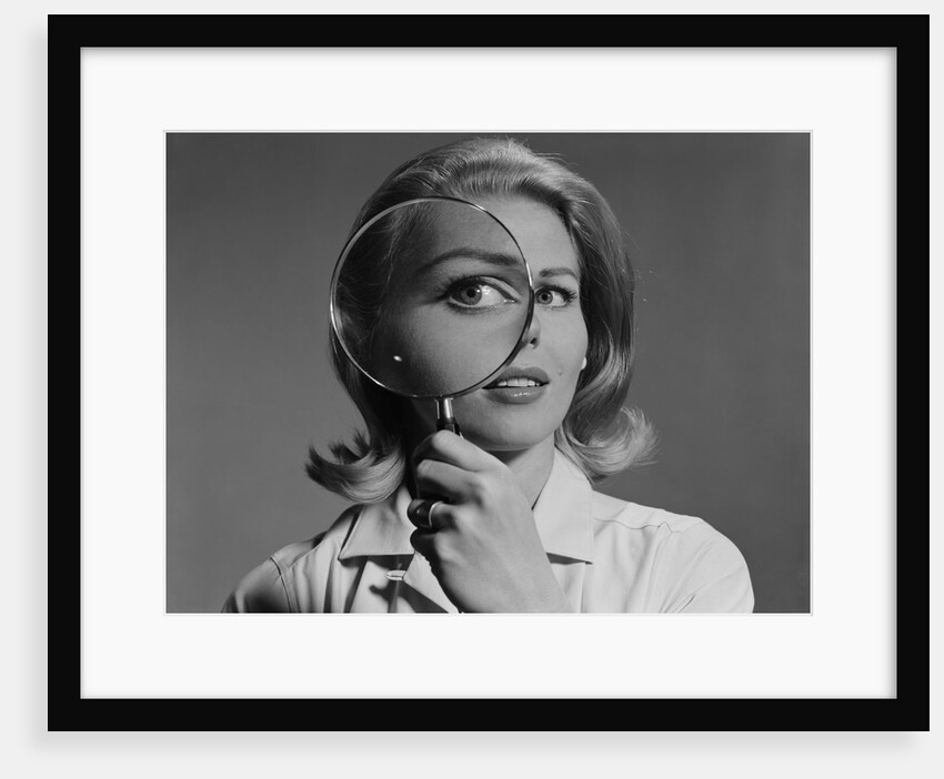 Blond woman magnifying glass held up to and enlarging one eye by Anonymous