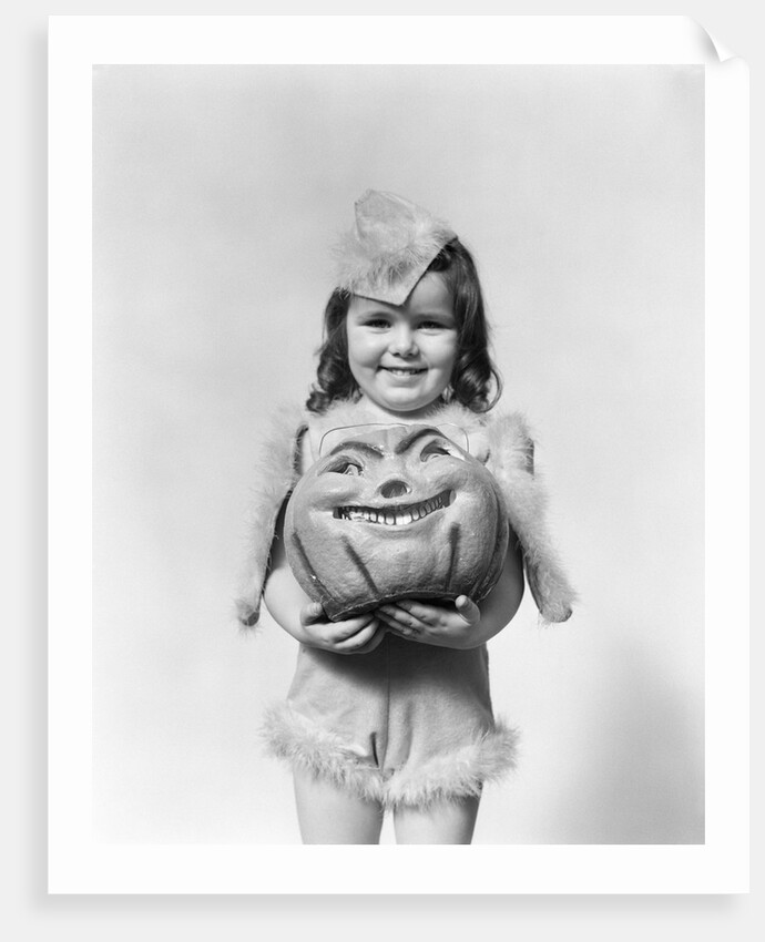 Happy smiling little girl in costume holding a papier-mache pumpkin head by Anonymous