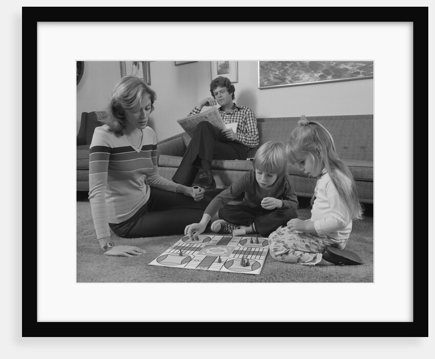 Family mother kids playing board game living room floor father reading newspaper by Anonymous
