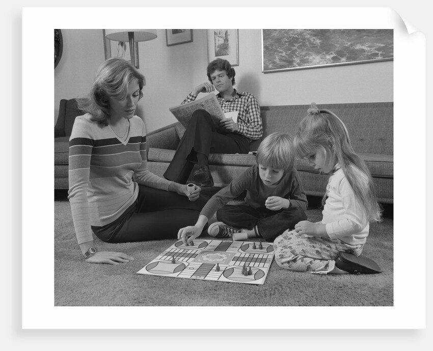Family mother kids playing board game living room floor father reading newspaper by Anonymous