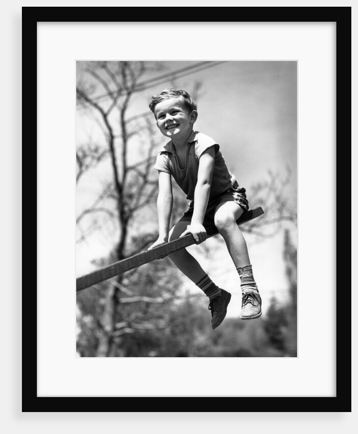Boy on seesaw smiling by Anonymous