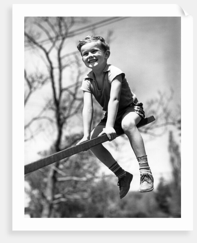 Boy on seesaw smiling by Anonymous