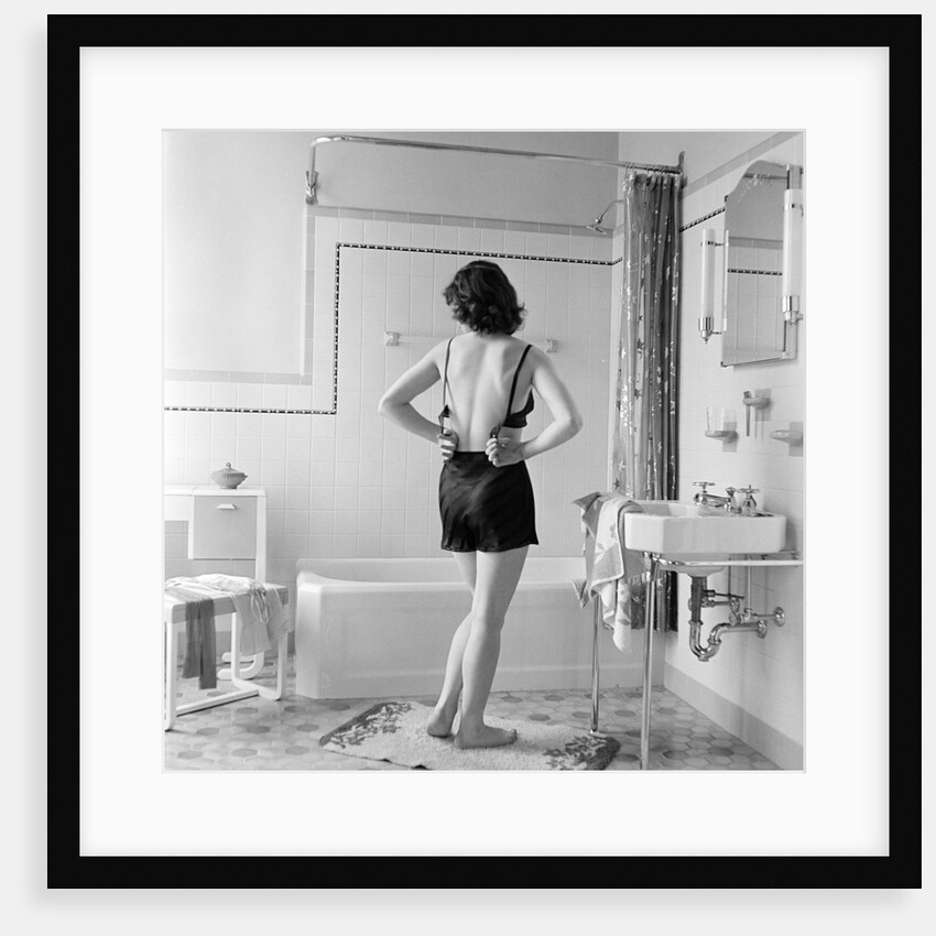 Back view of woman in bathroom fastening black bra by Anonymous