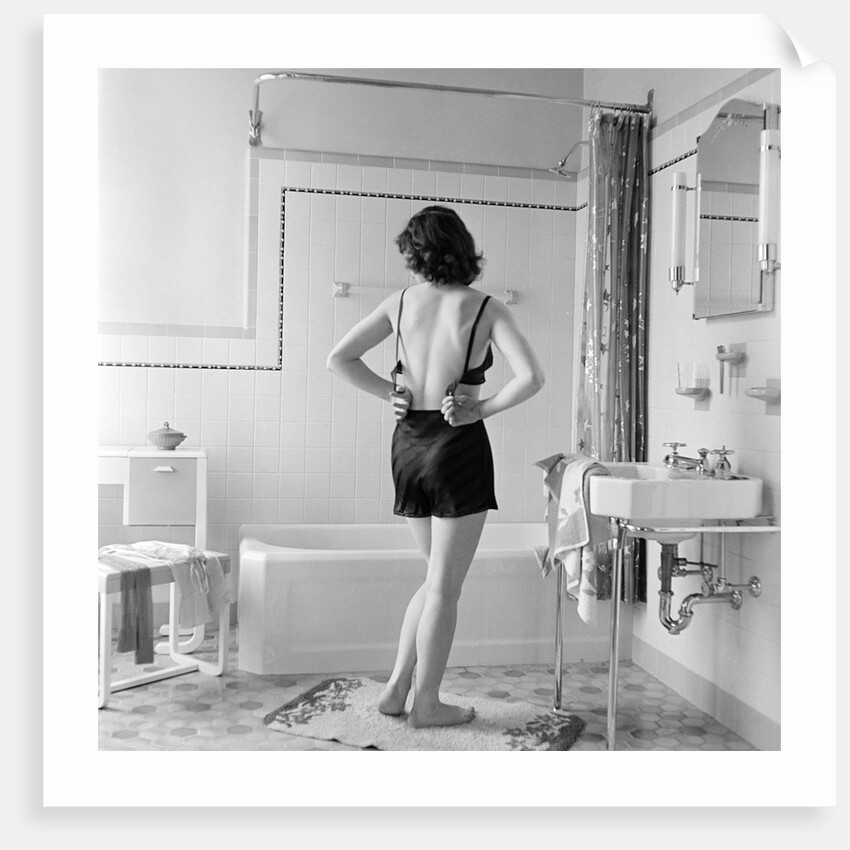 Back view of woman in bathroom fastening black bra by Anonymous