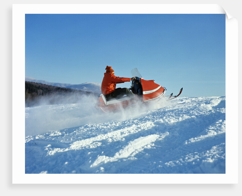 Man wearing red jacket and hat driving snowmobile by Anonymous