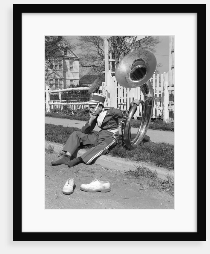Teen boy band uniform & tuba sitting on curb with shoes off by Anonymous