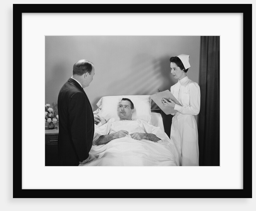 Man doctor woman nurse talking with male patient lying in hospital bed by Anonymous