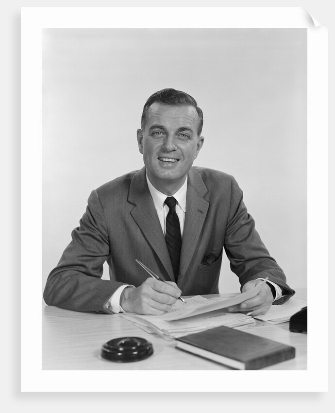 Smiling happy businessman pen in hand signing papers at desk by Anonymous