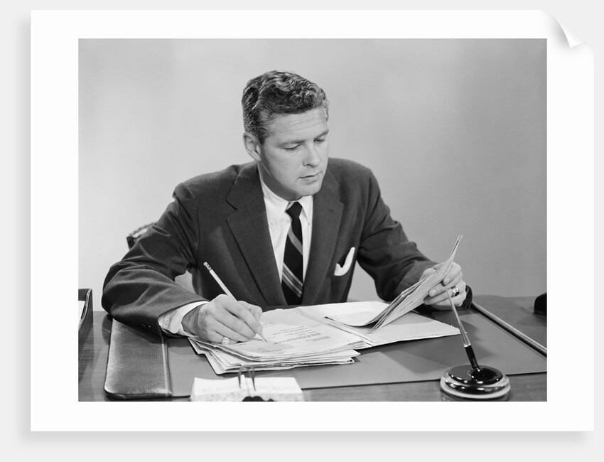 Businessman at desk looking over files papers making notes with pencil by Anonymous