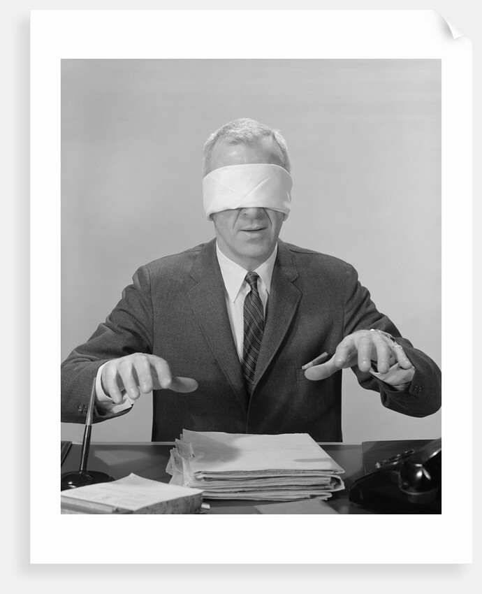 Business man hands hovering over desk wearing blindfold by Anonymous