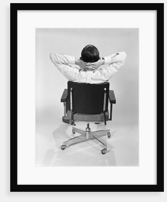 Man from behind sitting in office executive chair hands clasped behind neck by Anonymous