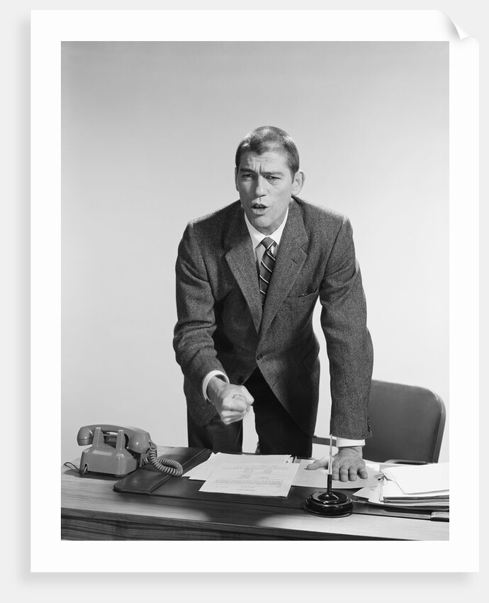 Angry upset businessman pounding fist into desk by Anonymous