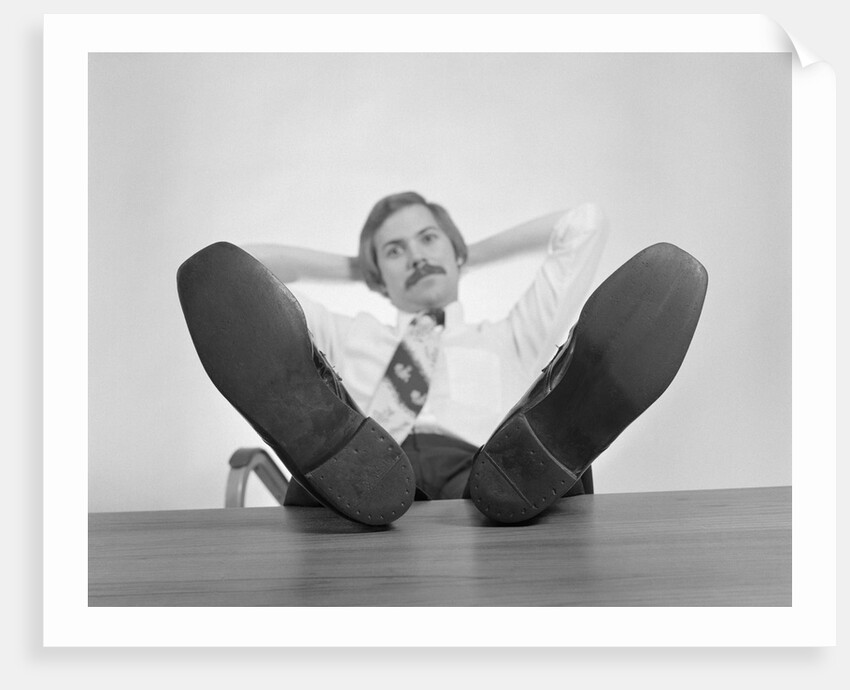 Businessman sitting feet up on desk by Anonymous