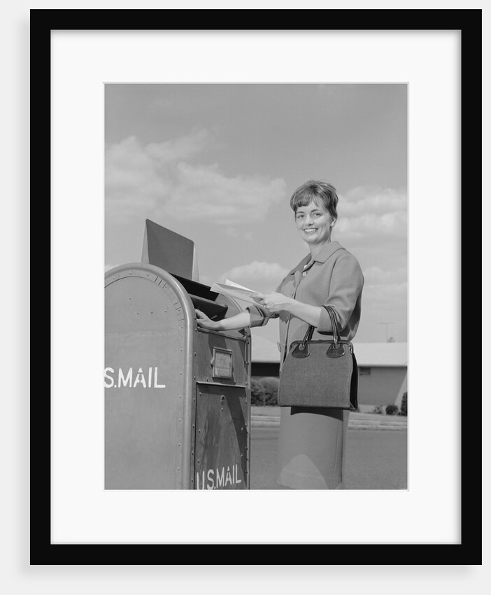 Smiling woman dropping letters in postal mail box by Anonymous