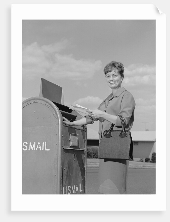 Smiling woman dropping letters in postal mail box by Anonymous