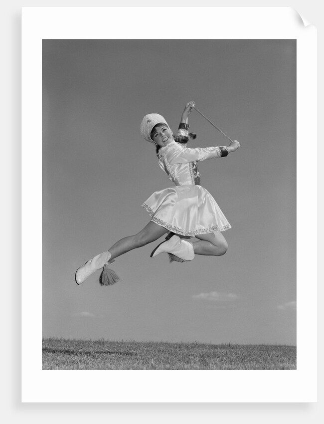 Woman majorette wearing band uniform holding baton jumping into the air by Anonymous