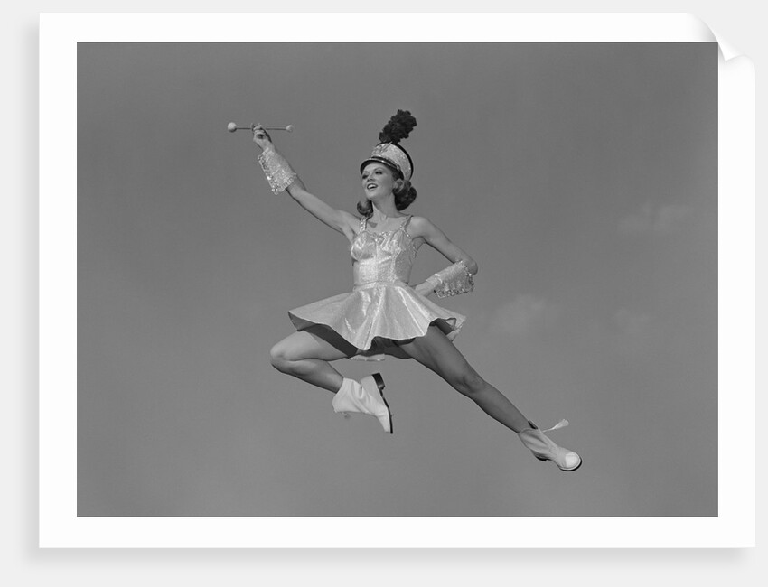 Woman majorette holding baton wearing short skirt uniform jumping into the air by Anonymous