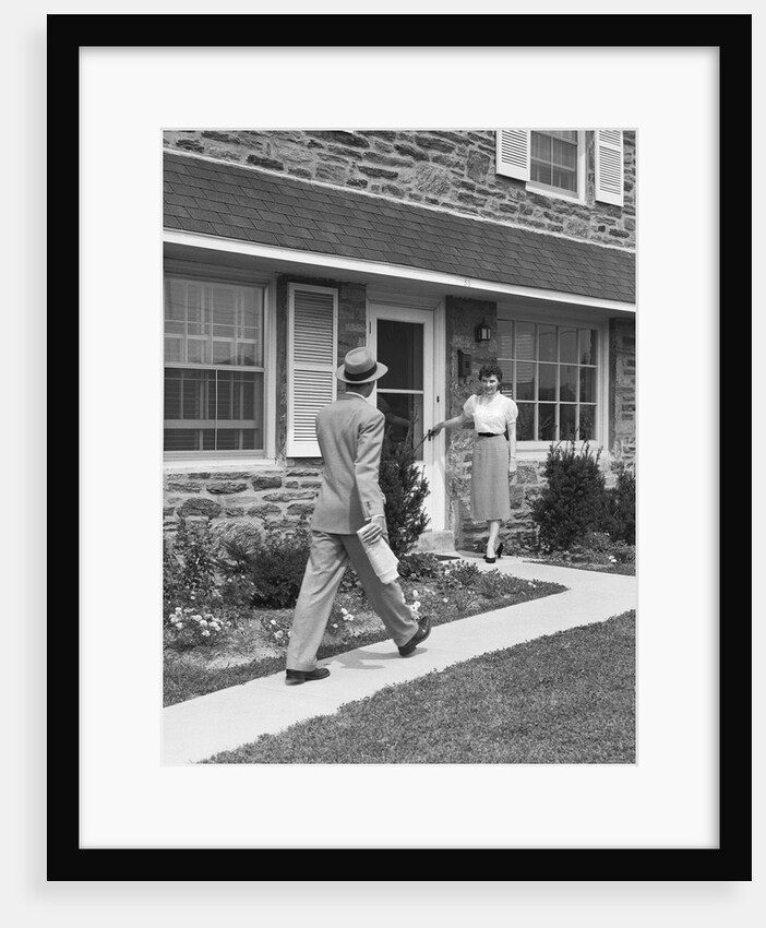 Man coming home down sidewalk woman waiting at door by Anonymous