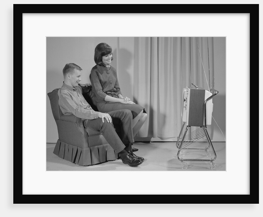 Couple man woman sitting chair watching portable television by Anonymous