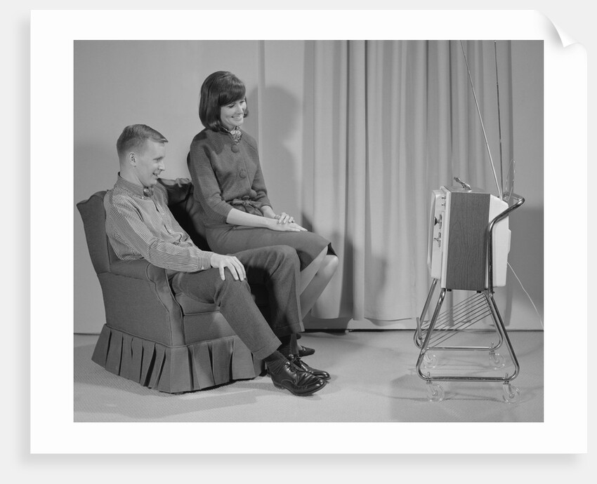 Couple man woman sitting chair watching portable television by Anonymous