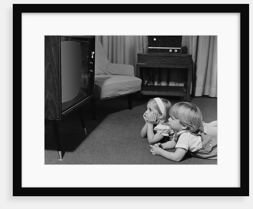 Two toddlers boy girl lying on floor watching television by Anonymous