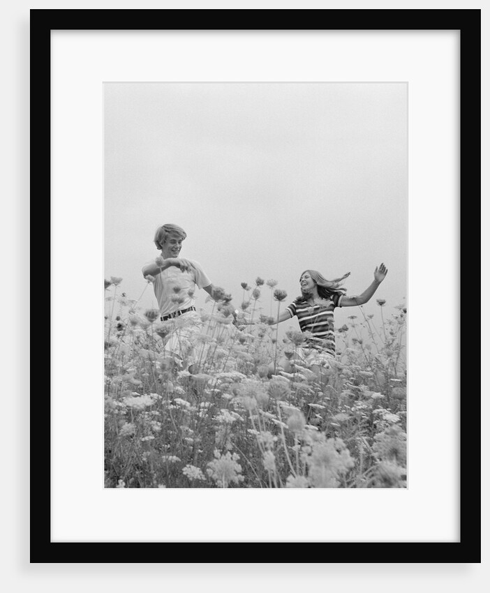 Young couple holding hands running through field of flowers by Anonymous