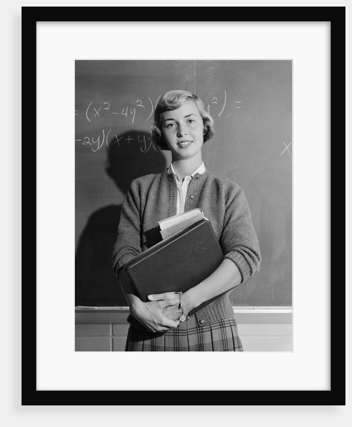 Teenage girl holding school books standing in front of blackboard by Anonymous