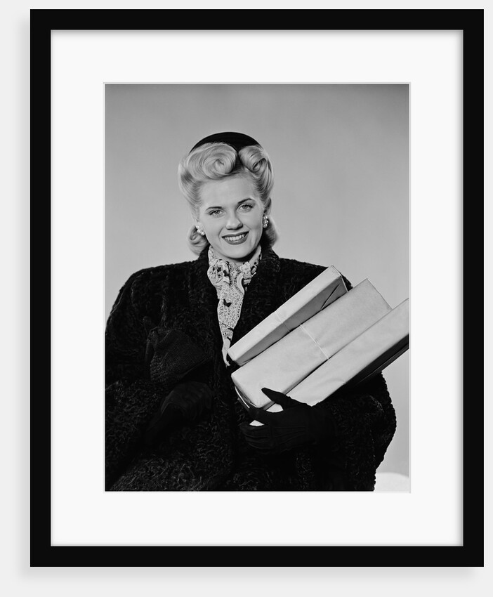 Blond woman smiling wearing winter coat carrying shopping parcel by Anonymous
