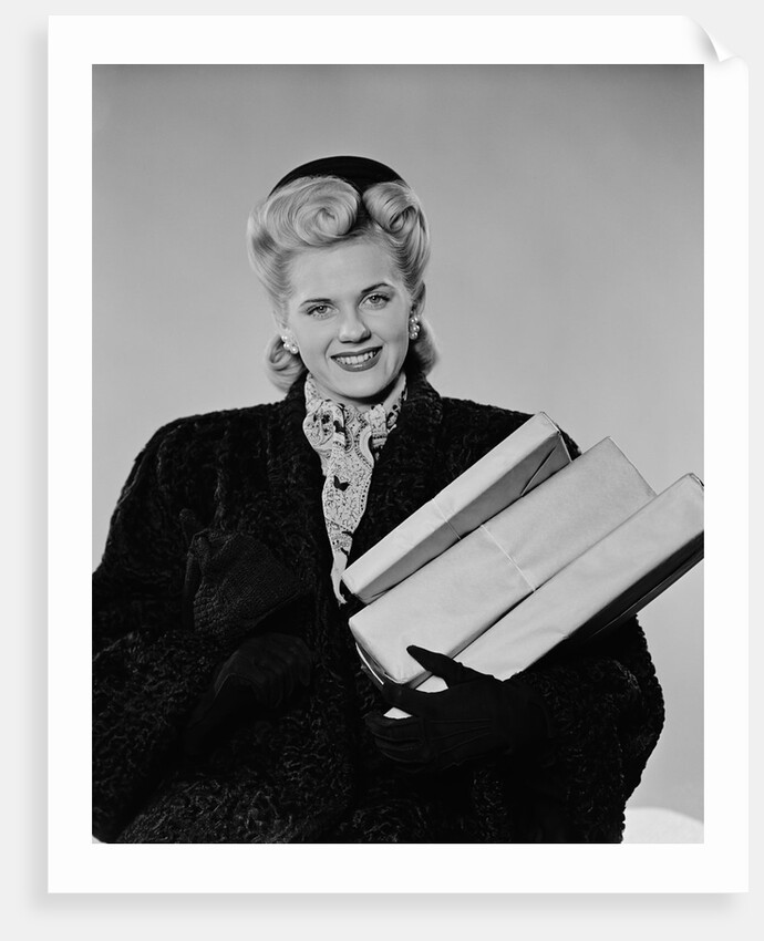 Blond woman smiling wearing winter coat carrying shopping parcel by Anonymous