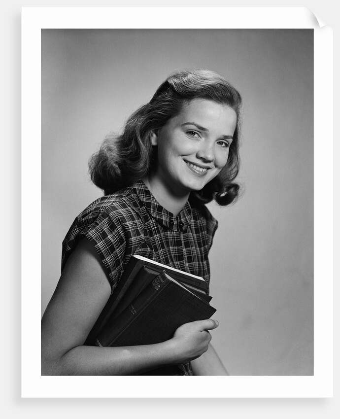 Young smiling woman holding books looking at camera by Anonymous