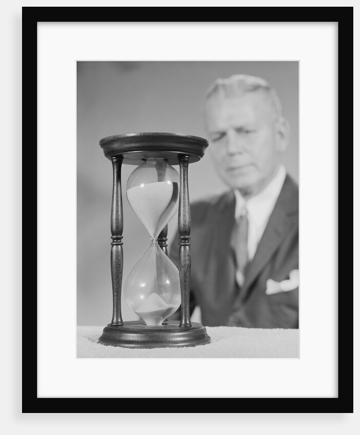 Elderly man soft focus behind hourglass by Anonymous