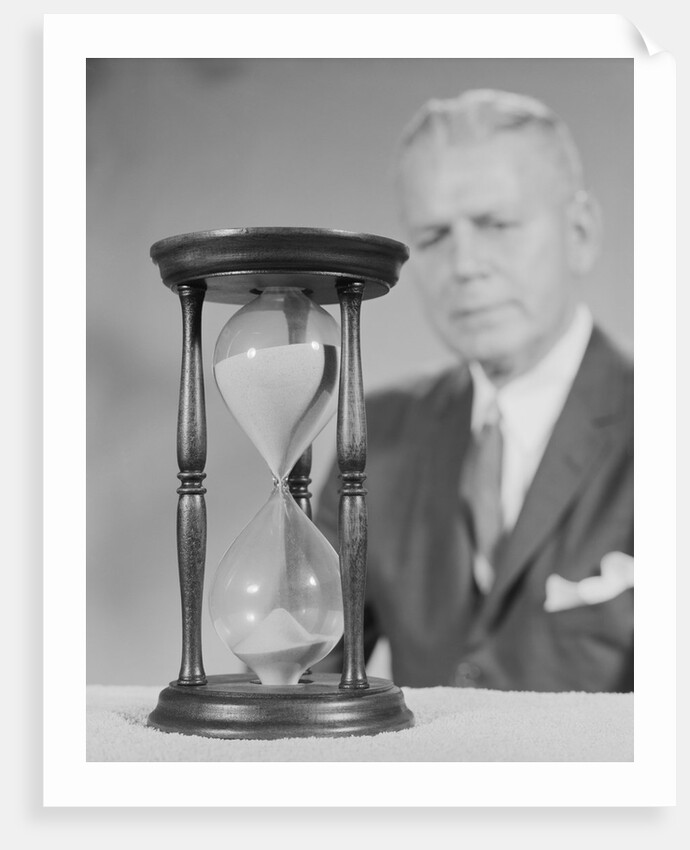 Elderly man soft focus behind hourglass by Anonymous
