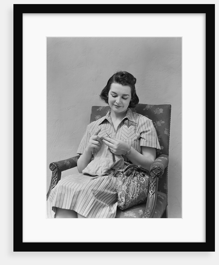 Brunette woman knitting sitting in armchair by Anonymous